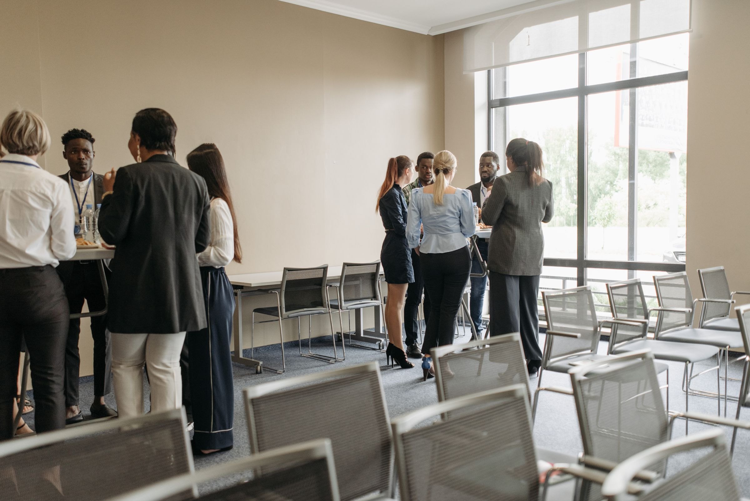 Professionals talking in small groups during a break at an industry event